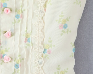Détail du haut à fleurs avec bordure en dentelle crème et trois roses en ruban rose