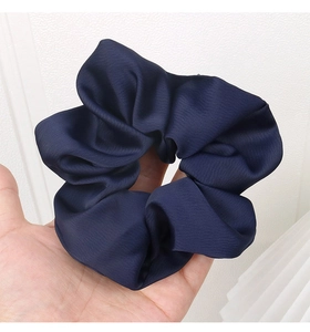 Detailed view of dark blue large satin scrunchie showing glossy fabric texture and folds