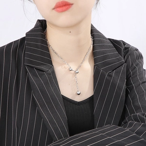 Collier en Y argenté en acier inoxydable avec perles sur un mannequin en costume noir