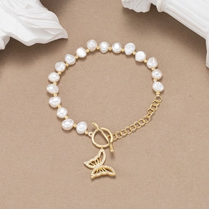 Détail du bracelet en perles baroques avec pendentif papillon doré et fermoir à bascule