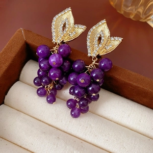 Macro detail of French vintage purple bead grape earrings with gold rhinestone leaf