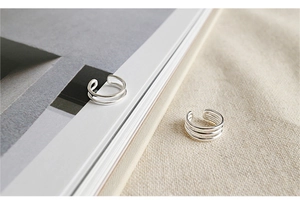 Minimalist S925 silver multi-layer ear cuff set displayed on white book and linen cloth