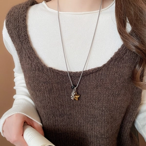 Detail of star pendant necklace with tiger eye texture on brown knitted vest
