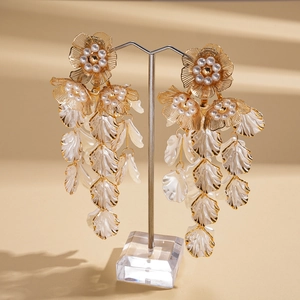 Detailed view of long shell leaf tassel earrings with gold flower and faux pearl accents