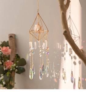 Detail view of pink crystal suncatcher with golden geometry creating rainbow light effects