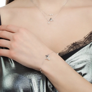 Close-up of S925 silver bird pendant bracelet and necklace with small pearls on model