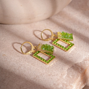 Dettaglio macro di orecchini vintage con strass verdi e montatura geometrica in oro