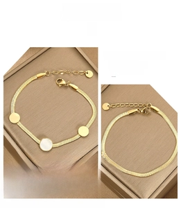 Detail view of golden flat snake bone chain bracelet with lobster clasp and round charms
