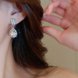 Close-up of sparkling silver crystal flower and teardrop earrings worn by a model