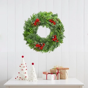 Christmas pine needle wreath with red berries and pinecones on a white wooden wall backdrop
