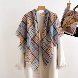 Detailed close-up of plaid cashmere-like scarf with tassels on beige coat