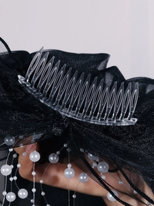 Detail of transparent hair comb with black mesh veil and hanging white pearl strands