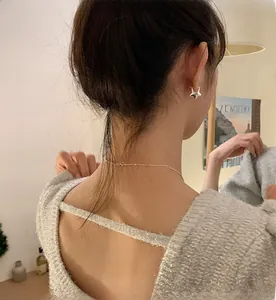 Dettaglio di orecchini a stella in argento e collana indossati da una modella in luce soffusa