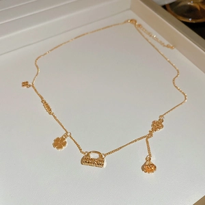 Macro view of 18k gold plated clover and flower charms on a delicate vintage necklace