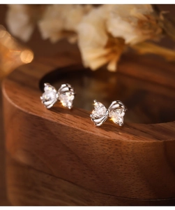 Macro shot of S925 silver heart bow stud earrings with sparkling cubic zirconia on wood