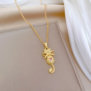 Elegant gold cat pendant necklace with red heart stone and crystal bow tie detail