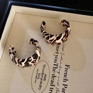 Detailed view of leopard print C-shape earrings with gold studs inside a jewelry box