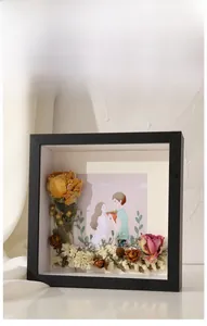 Detail of 3D black shadow box frame featuring dried roses and couple illustration