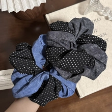 Close-up of denim fabric hair scrunchies with white polka dots on a wooden background