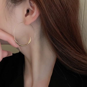 Close-up of elegant gold-plated geometric hoop earring worn by a model in detail