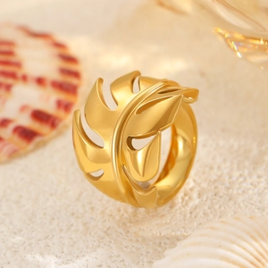 Detailed macro view of a gold leaf hollow-out ring on a beach and shell background