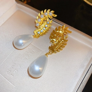 Detailed macro of vintage pearl leaf earrings with blue rhinestones and gold plating