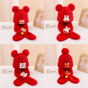 Detail of red knit kids hat and scarf set with cute rabbit embroidery and fur pompoms