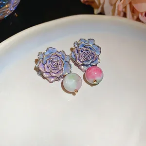 Elegant purple rose earrings with crackle beads and gold trim on white porcelain plate