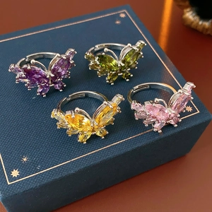 Détail de bagues papillon en zircon de quatre couleurs sur un écrin bleu marine