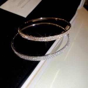 Close-up of elegant rose gold and silver pave-set diamond bangles on a jewelry box
