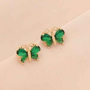 Elegant gold butterfly stud earrings with sparkling green zircon crystals on pink silk