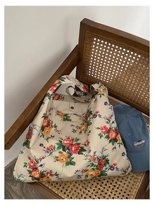 Floral canvas tote bag with red and yellow prints on a rustic wooden rattan chair