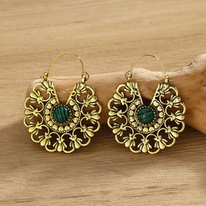 Detail of vintage gold bohemian earrings with green turquoise stone on rustic wood