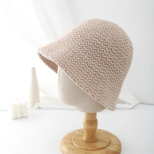 Detailed knit texture of beige wool cloche bucket hat on a boutique mannequin stand