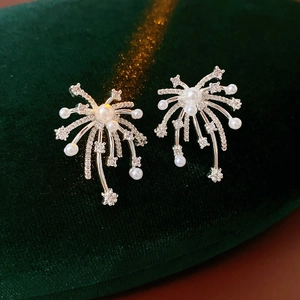 Macro shot of silver fireworks earrings with pearls and crystals on green velvet