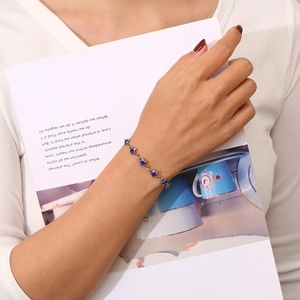Detail of a delicate silver chain bracelet with blue star-shaped zircon stones on a wrist