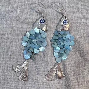 Fish-shaped shell tassel earrings with blue scales and silver evil eye detail
