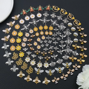 Vibrant mix of bee and daisy enamel charms arranged in a creative spiral pattern