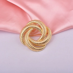 Elegant gold knot brooch with detailed texture on a soft pink satin background