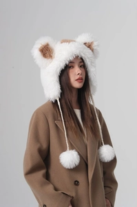 Detail of white plush ear-protection hat featuring cute bear ears and braided ball ties