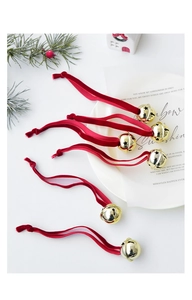 Close-up of golden hollow Christmas bells with red velvet ribbons on festive table