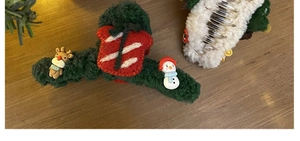 Detail view of plush Christmas elk hair clips with reindeer and snowman on wood base