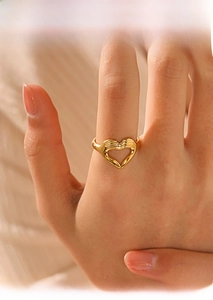 Détail d'une bague geste de cœur plaquée or portée sur la main d'un modèle