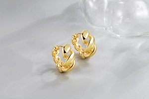 Detailed view of chunky twisted gold hoop earrings with a polished metallic spiral design