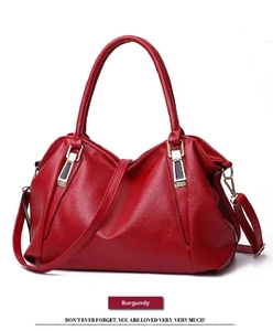 Detail of wine red pebbled leather handbag with spacious design and gold hardware