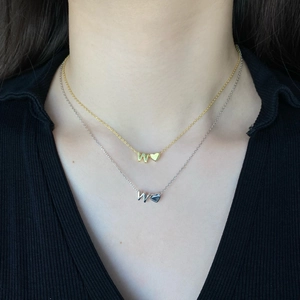 Close-up of S925 silver gold and silver necklaces with letter W and heart pendants