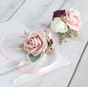 Close-up of artificial rose wrist corsages with pink ribbons and golden bead accents