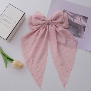 Pink chiffon bow hair clip with long streamers and textured polka dot pattern