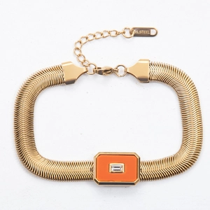 Detail of gold snake chain bracelet with orange enamel piece and crystal stone