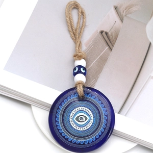 Detail of blue evil eye glass pendant with braided rope and lucky eye beads on a book
